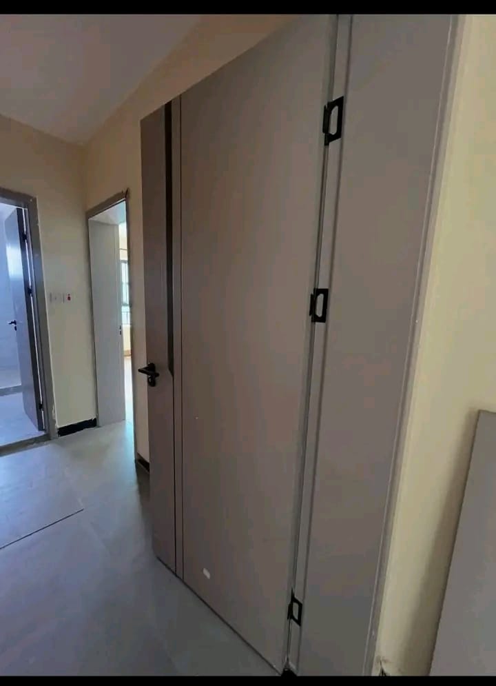Grey flush door with black hinges installed in a hallway