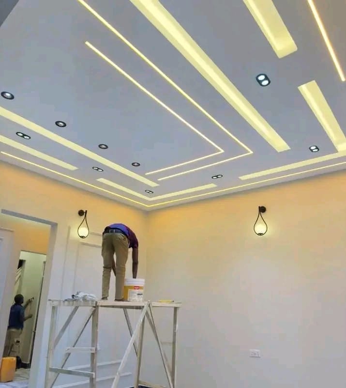 Painters finishing walls under an LED strip gypsum ceiling